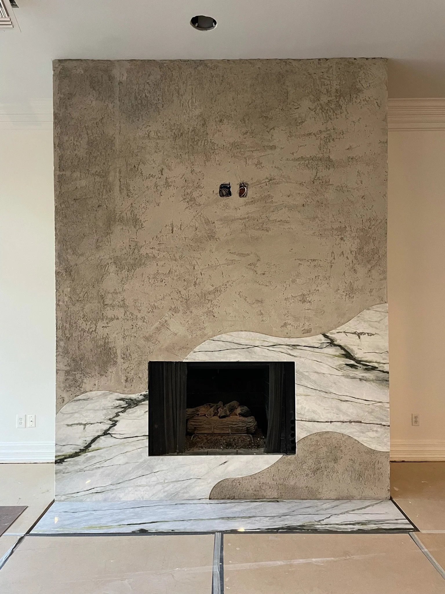 Fireplace wrapped around in stone cut with funky waves, evoking the landscapes of Baijou.
