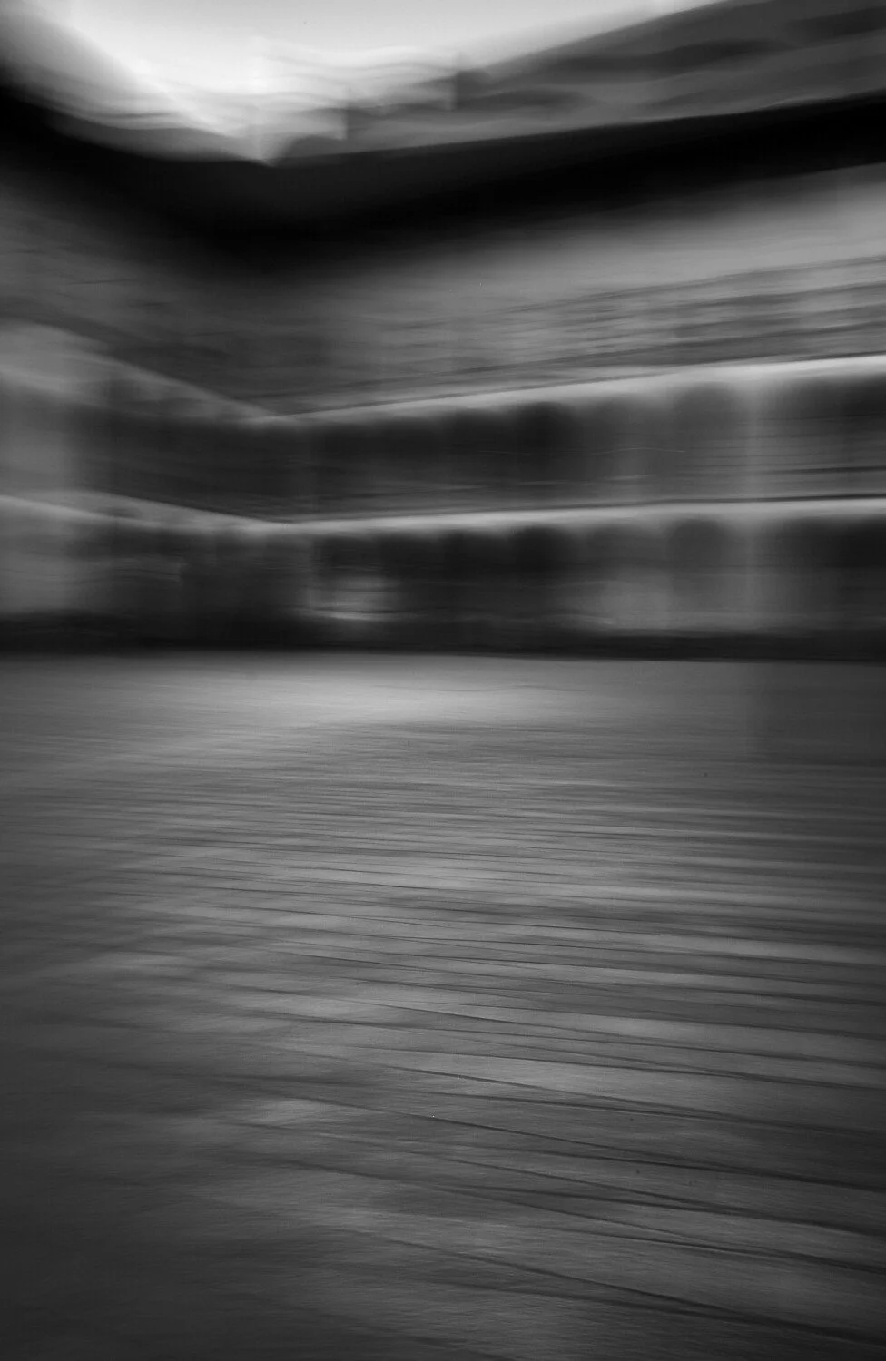 Blurred black and white image of a building exterior with horizontal lines and patterns.