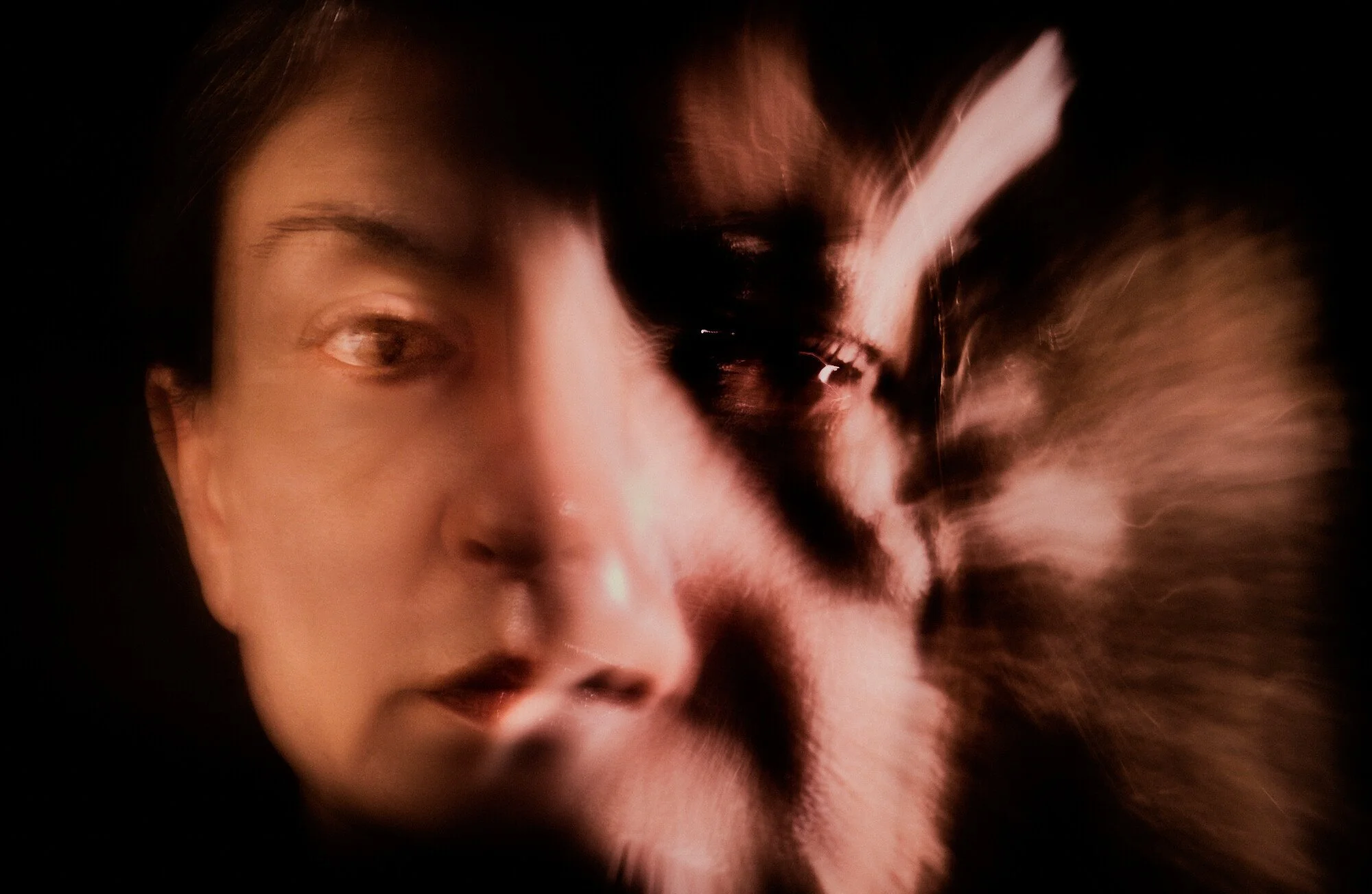 A close-up of a woman's face combined with another person's face, with a swirling motion, creating a double exposure effect.