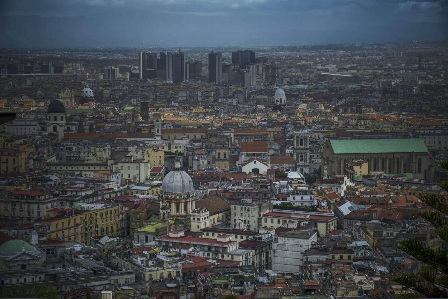 Aerial view of Milan, Italy showcasing historic and modern buildings, including domes, church towers, and skyscrapers under a cloudy sky.