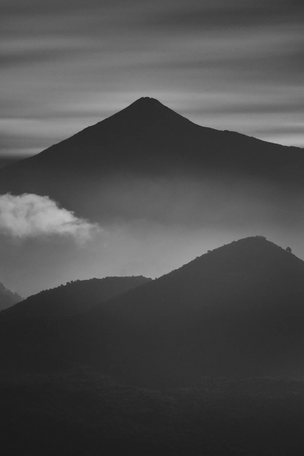 Black and white photo of a mountain landscape with two prominent mountains and a cloudy sky.