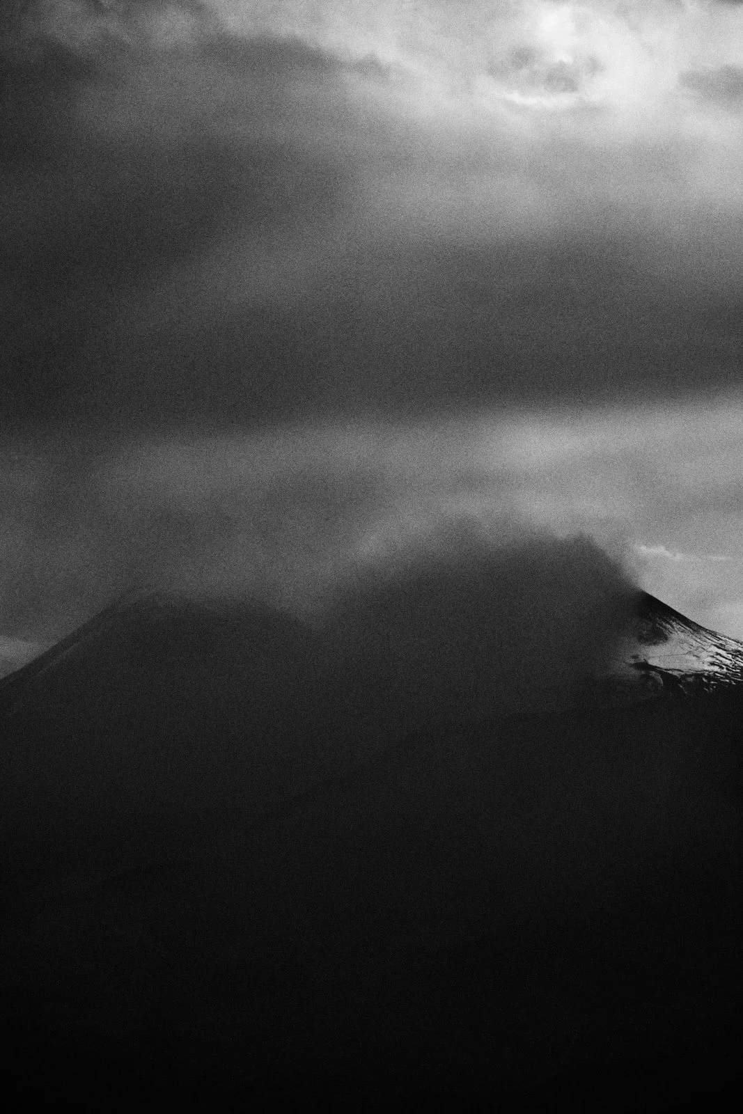Summit of Mount Etna emerging from heavy cloud in dark monochrome, Sicily — Whispers of Form by Tom Imio