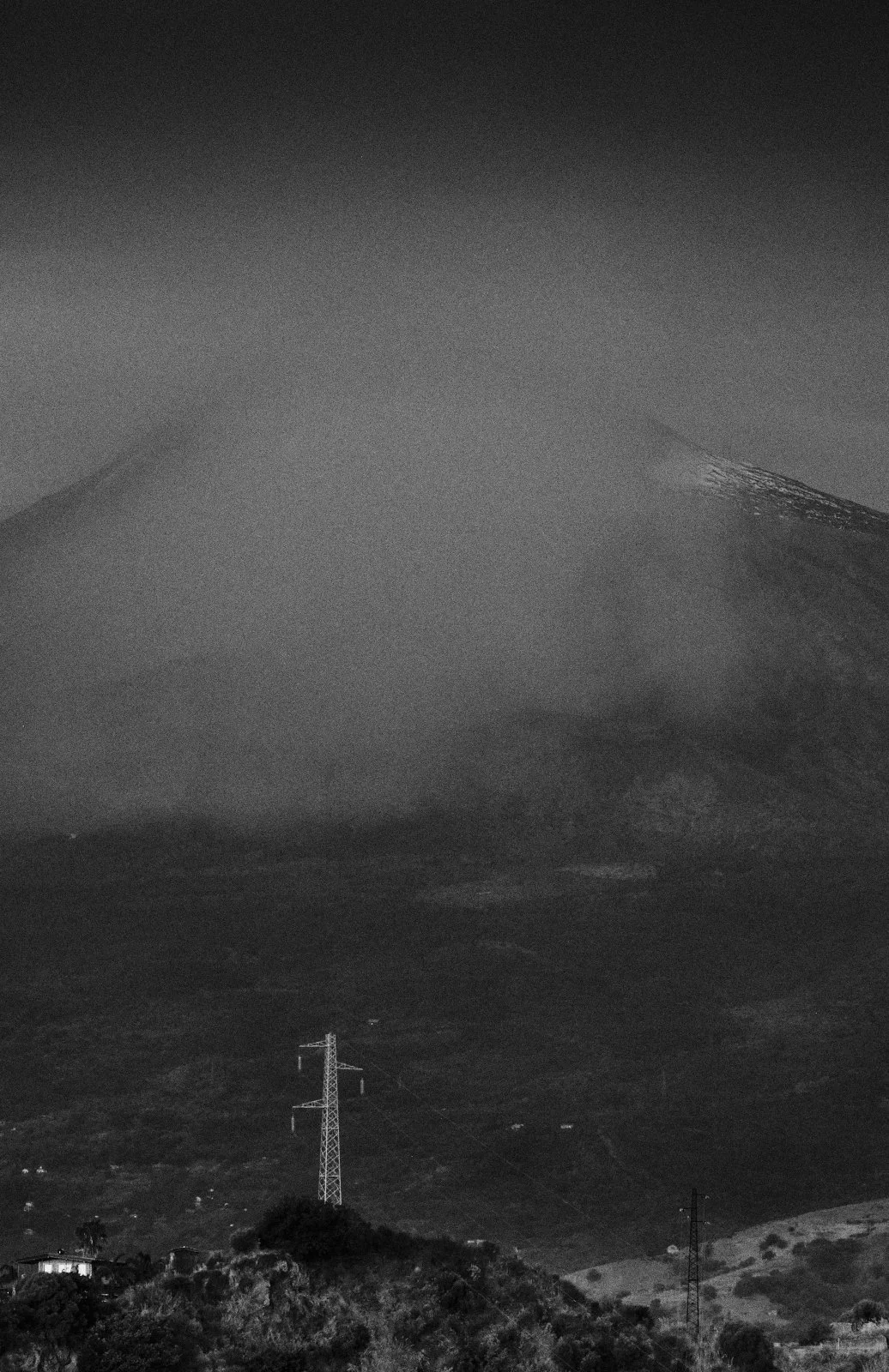 Electricity pylon on a hillside below Mount Etna half-veiled in cloud, Sicily — Whispers of Form by Tom Imio