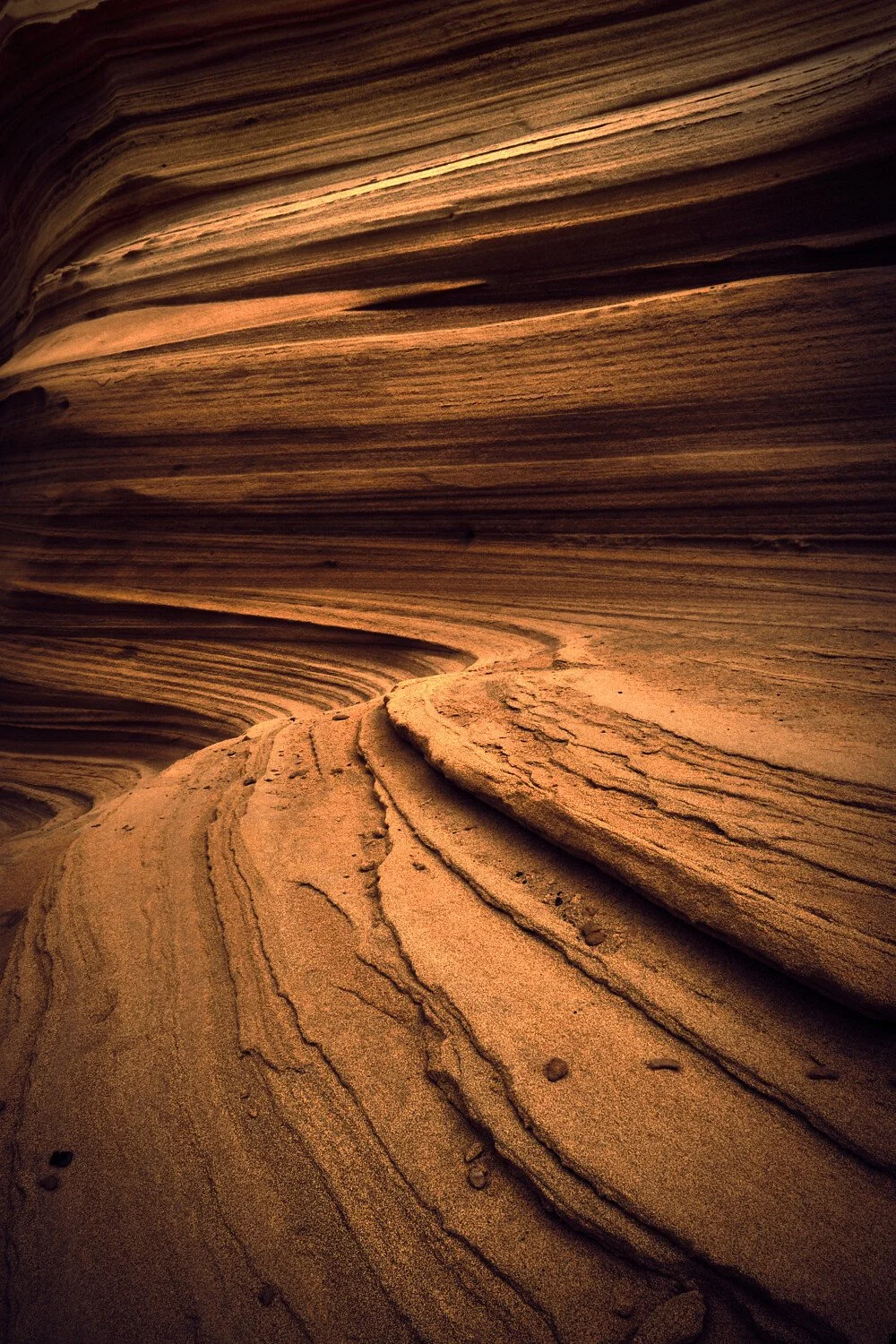 Layered sandstone rock formations with curved lines and striations in a desert landscape.