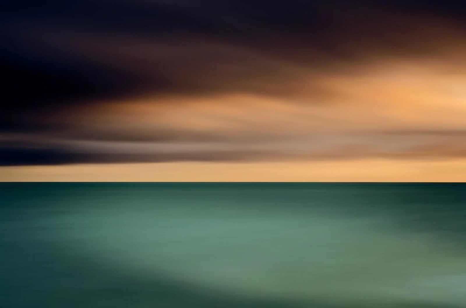 In a long exposure technique image of the Irish Sea under a cloudy sky during sunset