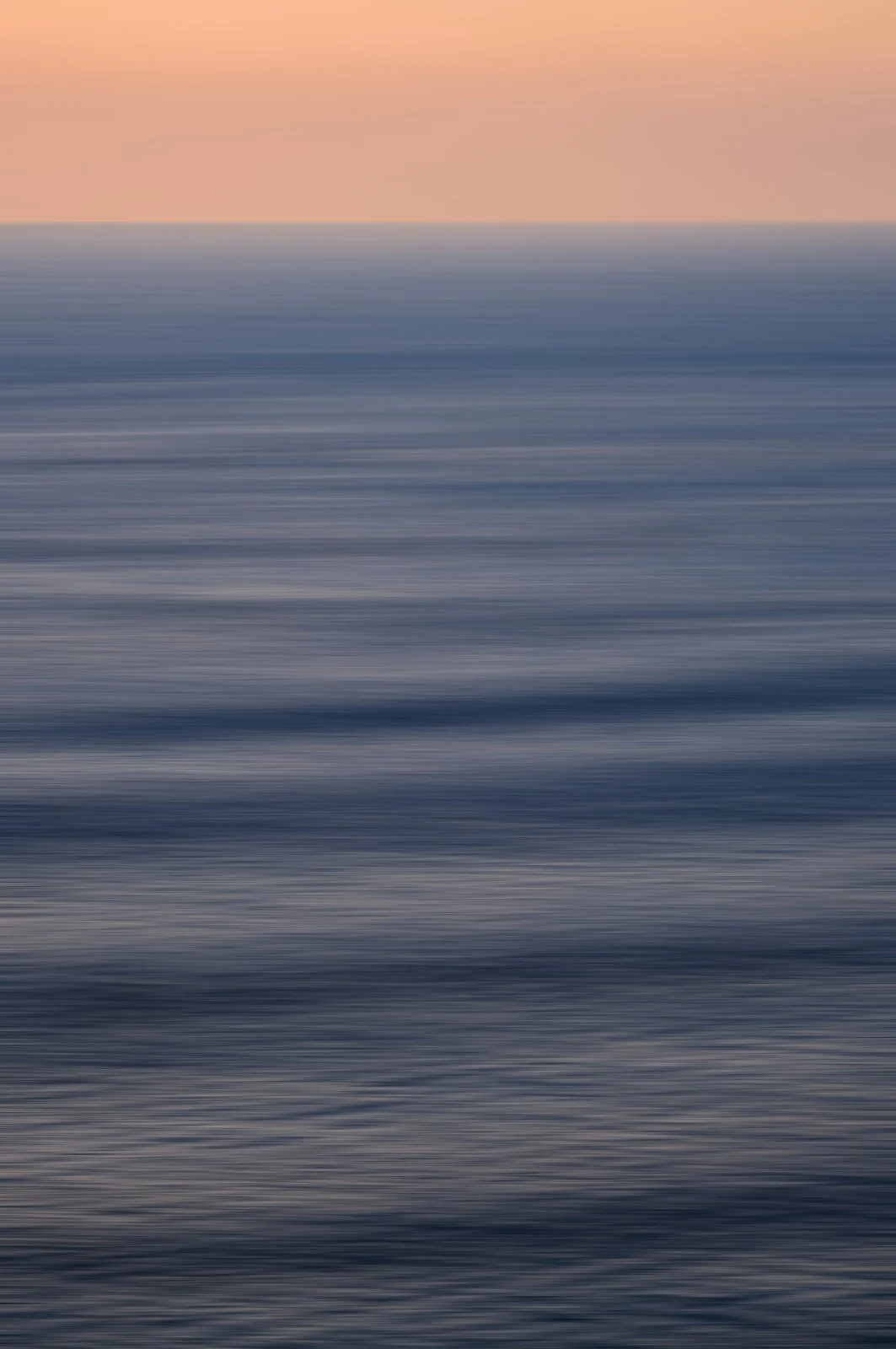 Long exposure abstraction of the Ionian Sea at dusk, blue water beneath a peach-coloured sky, Sicily — Mare Incognitum by Tom Imio