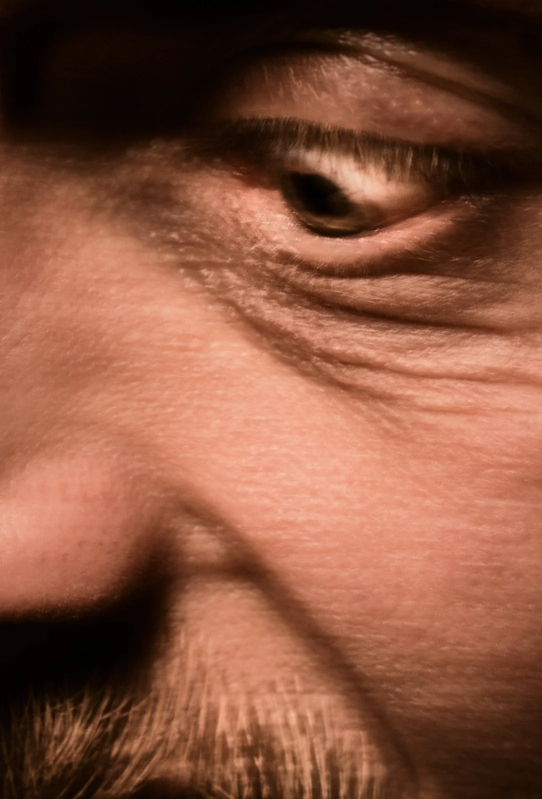 Close-up of a person's eye and surrounding skin, showing fine details and wrinkles.