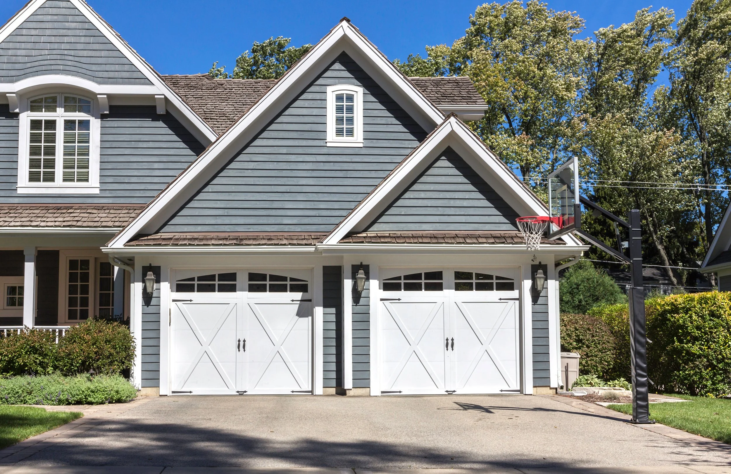 White carriage-style double garage doors with windows on a blue home