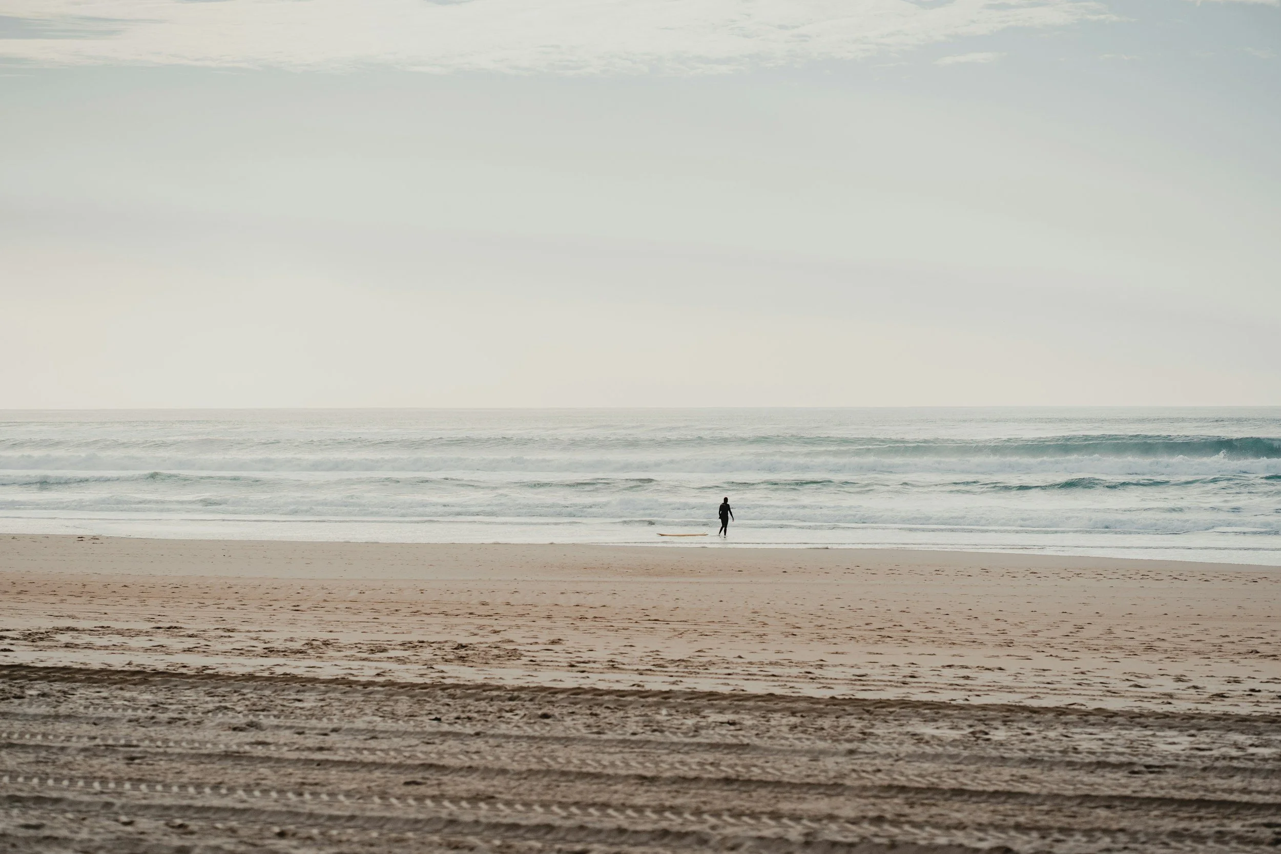 ocean meets the shore with single individual on beach
