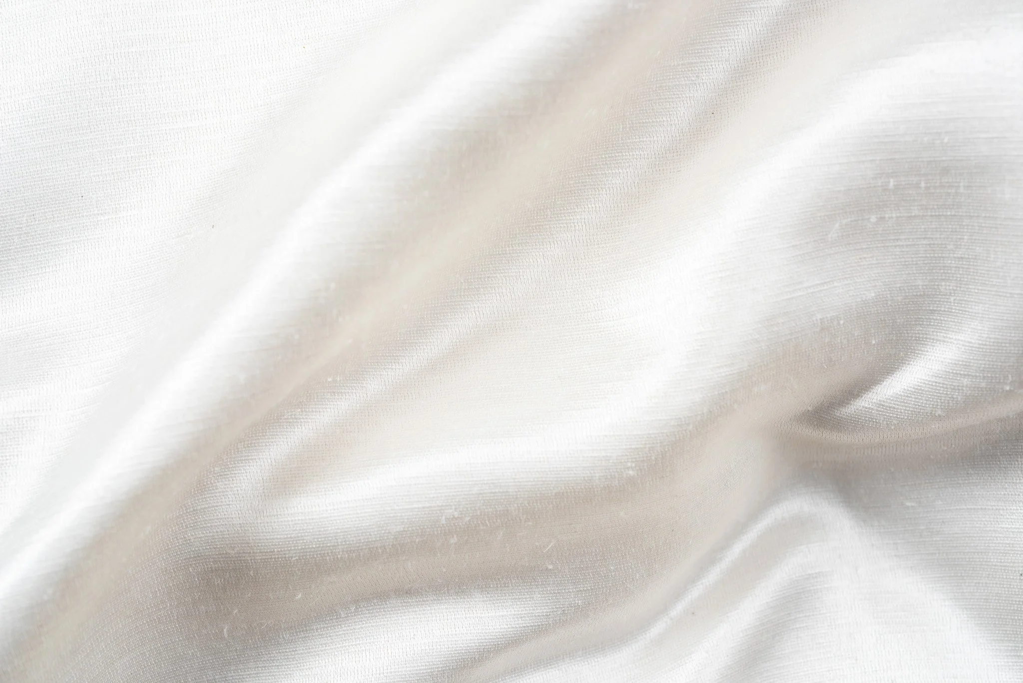 Nahaufnahme von weißem, glänzendem Seidenstoff mit weichen Falten
