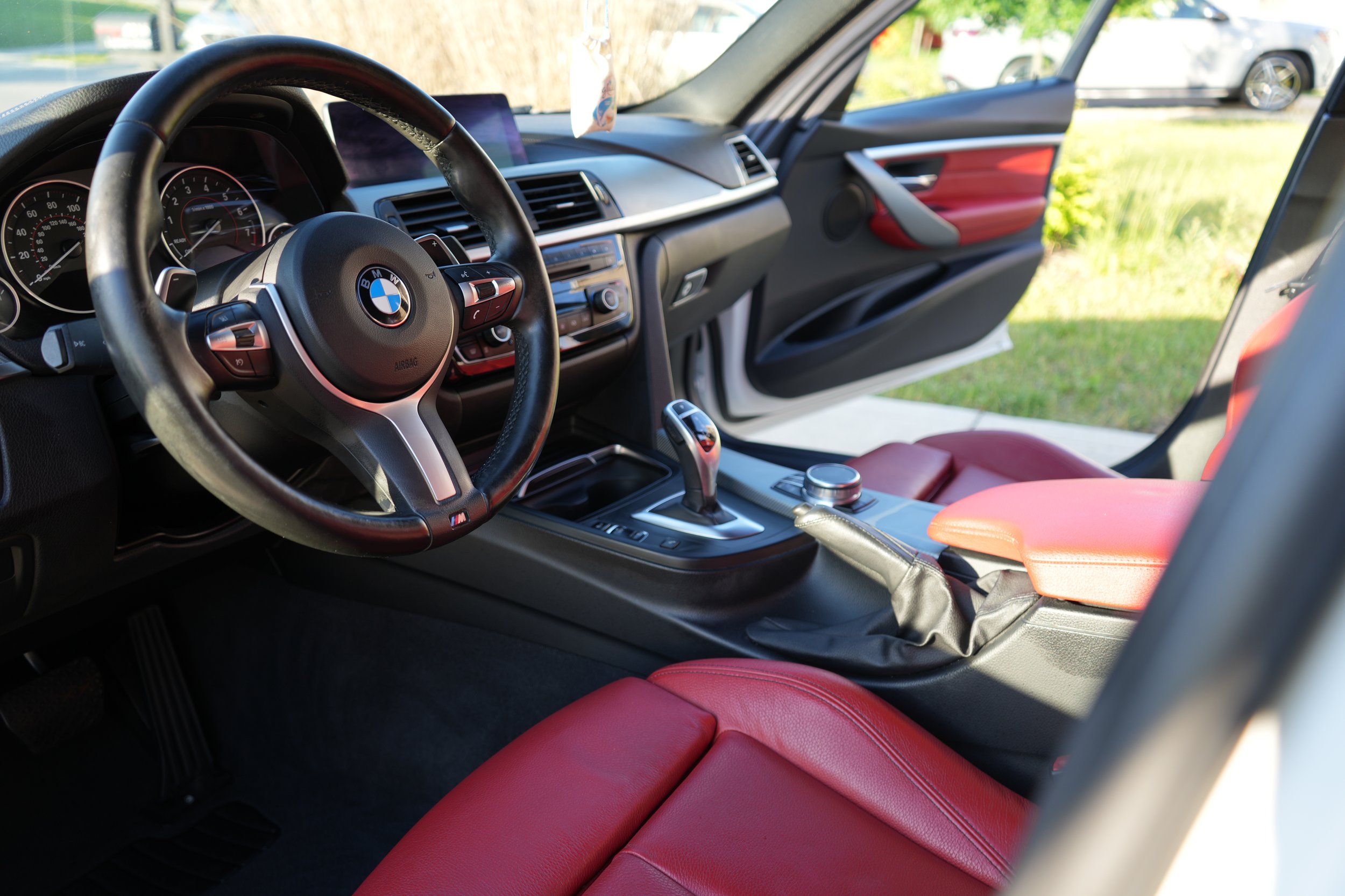 Interior of a BMW car with red leather seats and a modern dashboard.