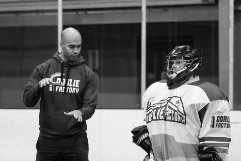 Ice hockey coach instructing goalie wearing protective gear