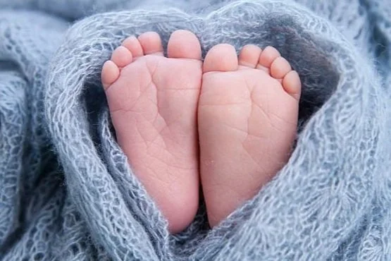 Two baby feet wrapped in a soft blue blanket.