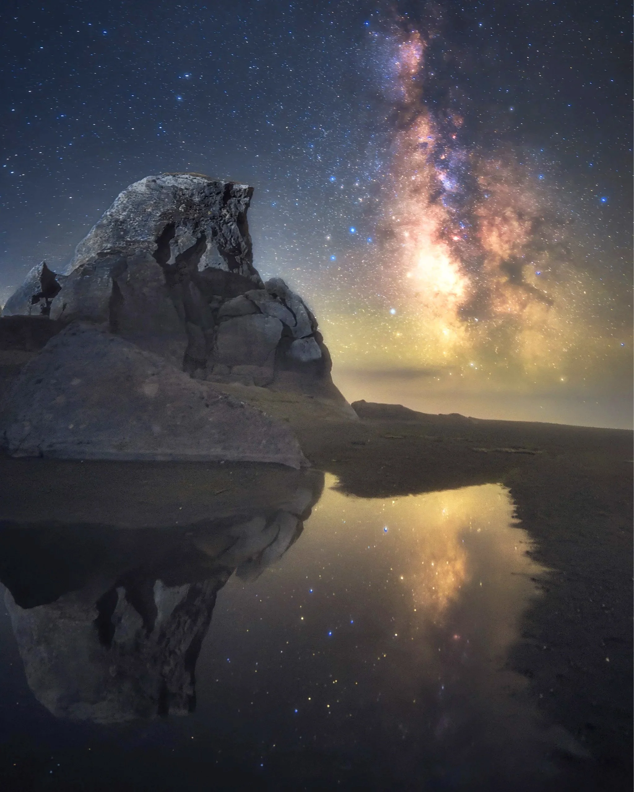 Milky Way rising beside Kissing Rock along the Oregon Coast and reflecting in tide pool at night.