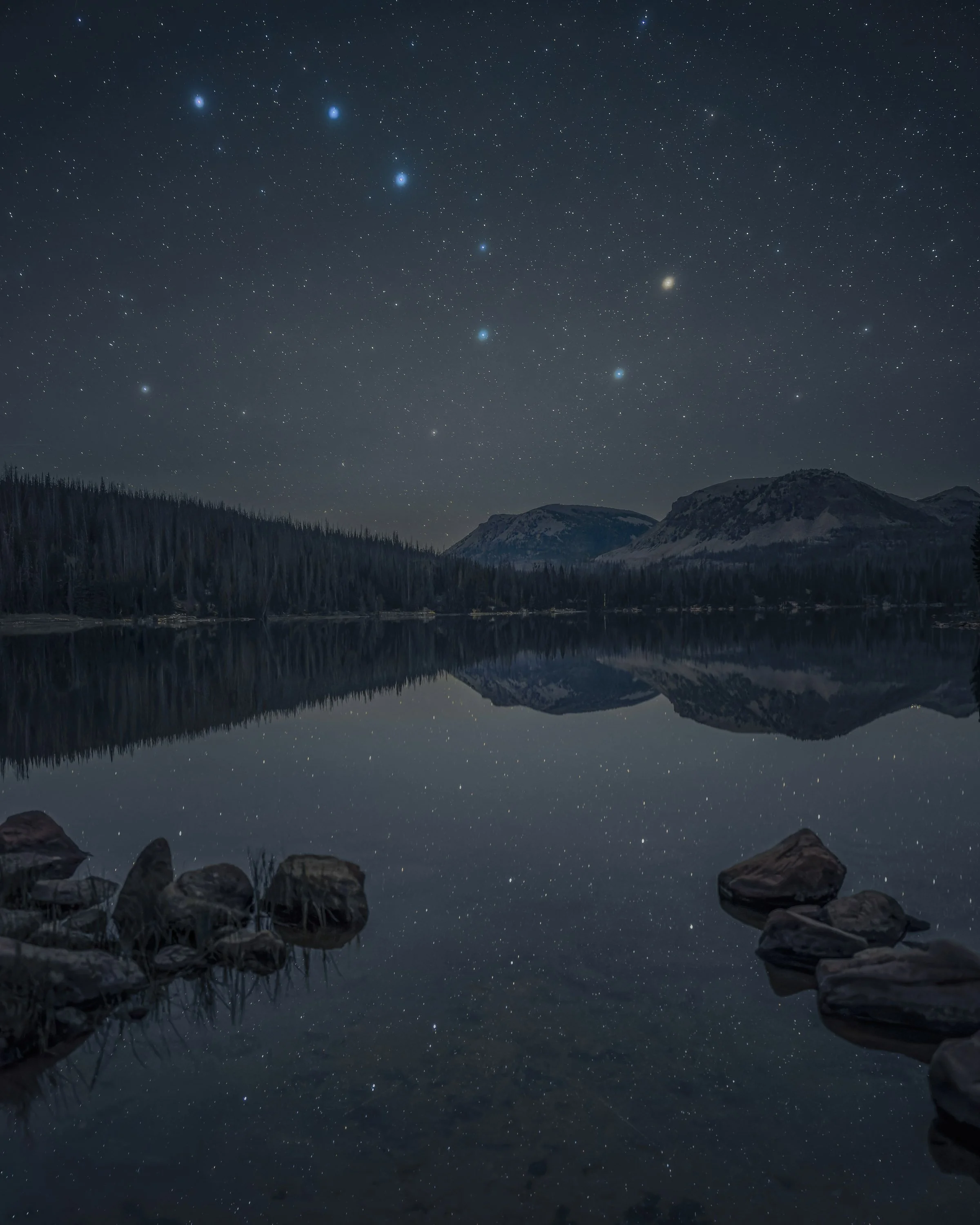 Big Dipper above a calm alpine lake with stars and mountains reflected in the water in Utah’s Uinta Mountains.