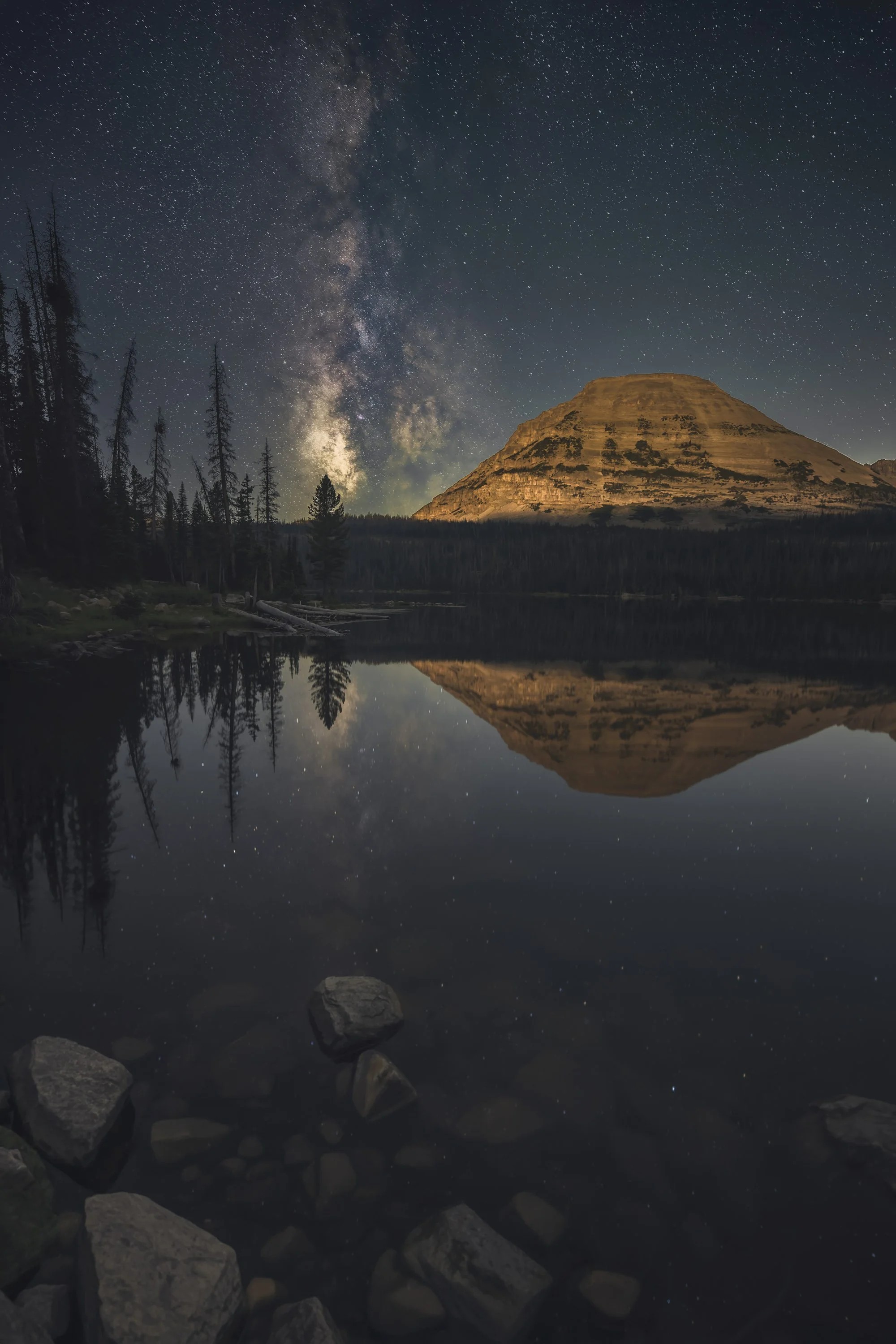 Milky Way rising beside a mountain and reflecting in a calm alpine lake in Utah’s Uinta Mountains.