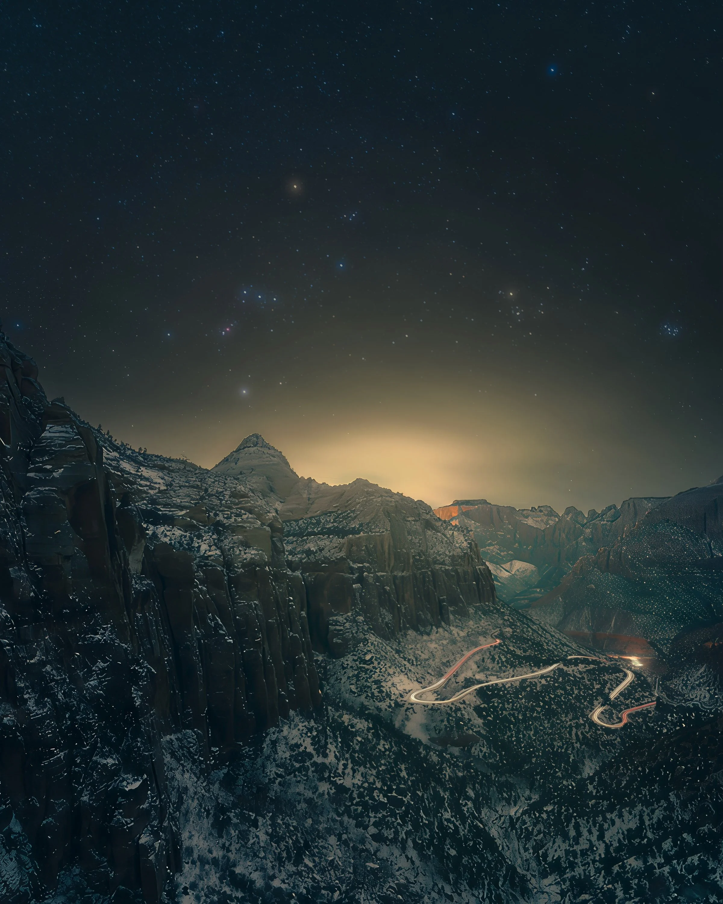 Orion above snow-covered Zion Canyon Overlook with winding vehicle light trails through Zion National Park, Utah.
