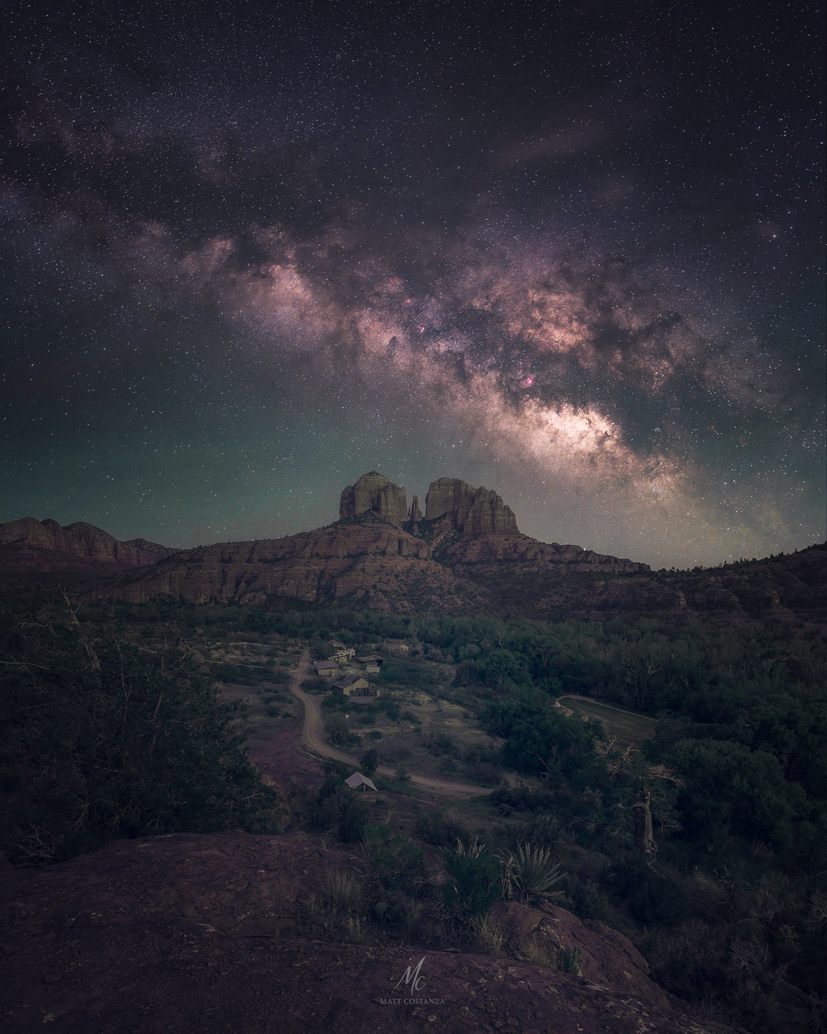 A panoramic night view of the Milky Way stretching above Cathedral Rock in Sedona, Arizona, captured from above Crescent Moon Ranch with detailed star fields and desert foreground.