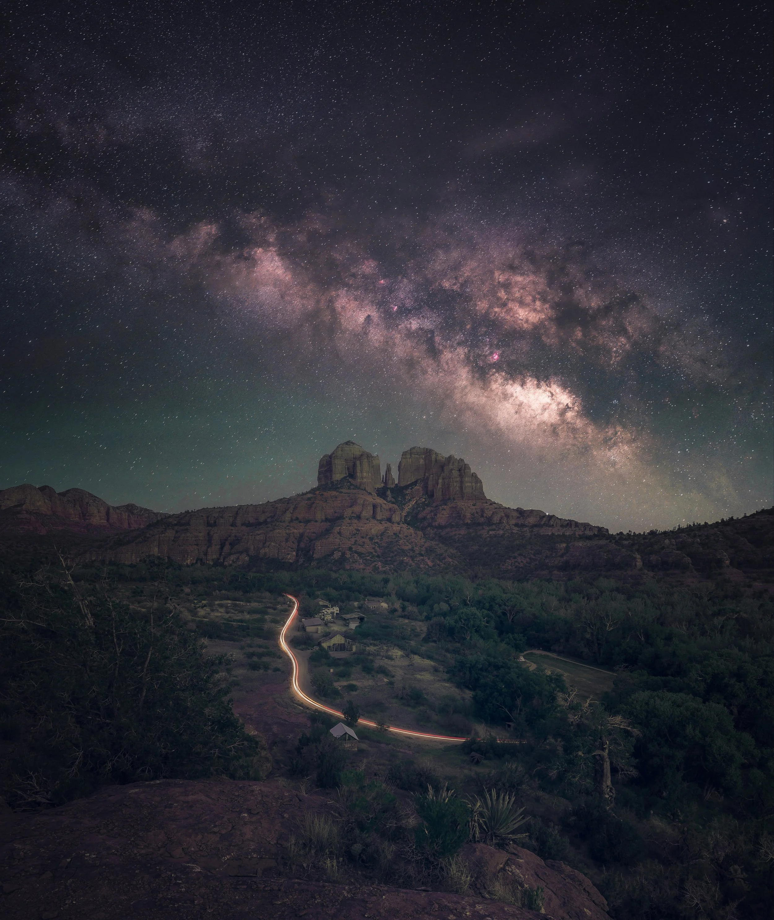 Milky Way stretching above Cathedral Rock and a winding light trail in Sedona, Arizona.