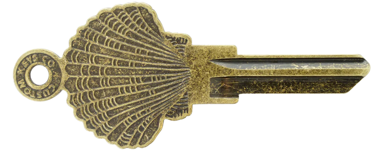 A key with a seashell-shaped head and a circular hole at the top.