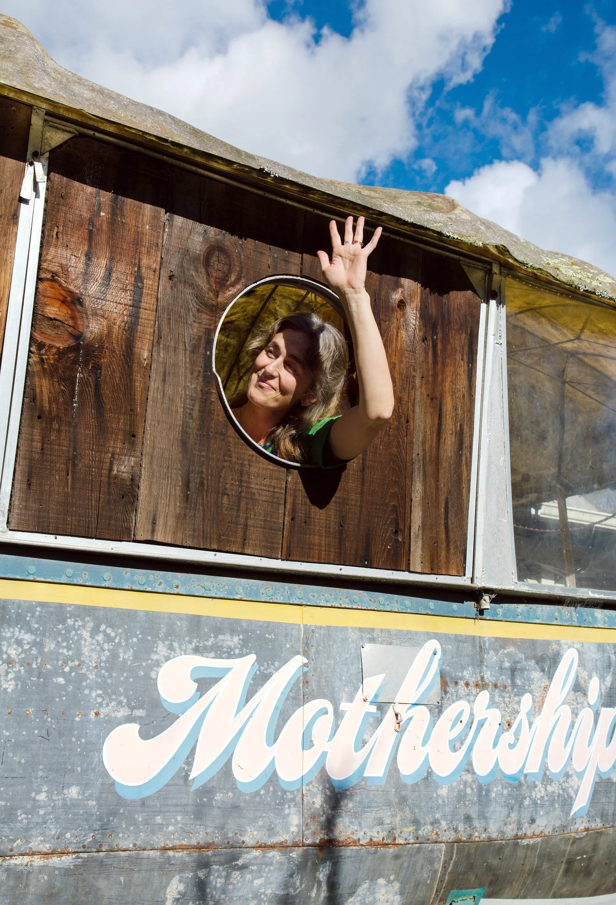 Bronwen Murch waving from the port hole of the Mothership Vintage, a charming vintage shop in Bolinas, California.