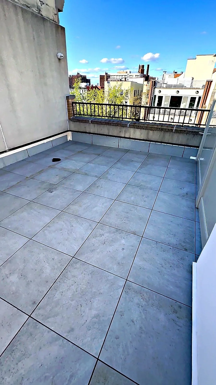 Completed rooftop terrace by Raimo Renovations - large-format porcelain tile over a waterproofed deck with steel guardrail