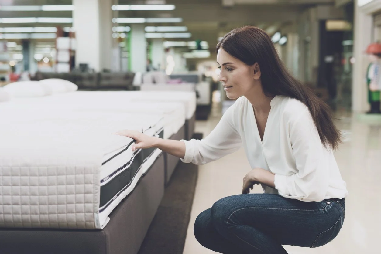 Woman shopping for discount mattress in appointment-only store.