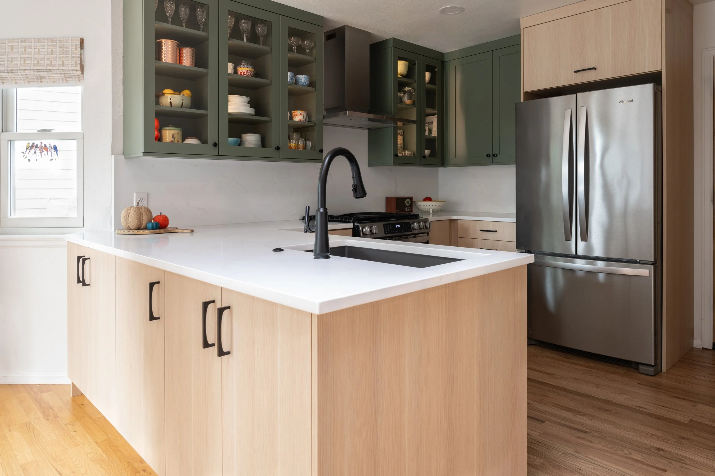 Highlands Ranch kitchen remodel with green cabinets, natural wood peninsula, and white countertops