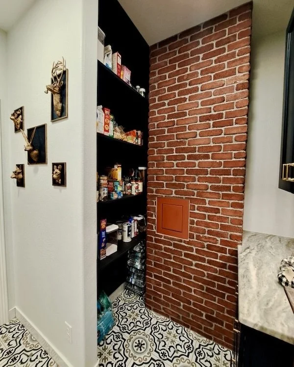 Custom pantry and storage area featuring exposed brick accents, open shelving, and patterned tile for a warm industrial-inspired look.