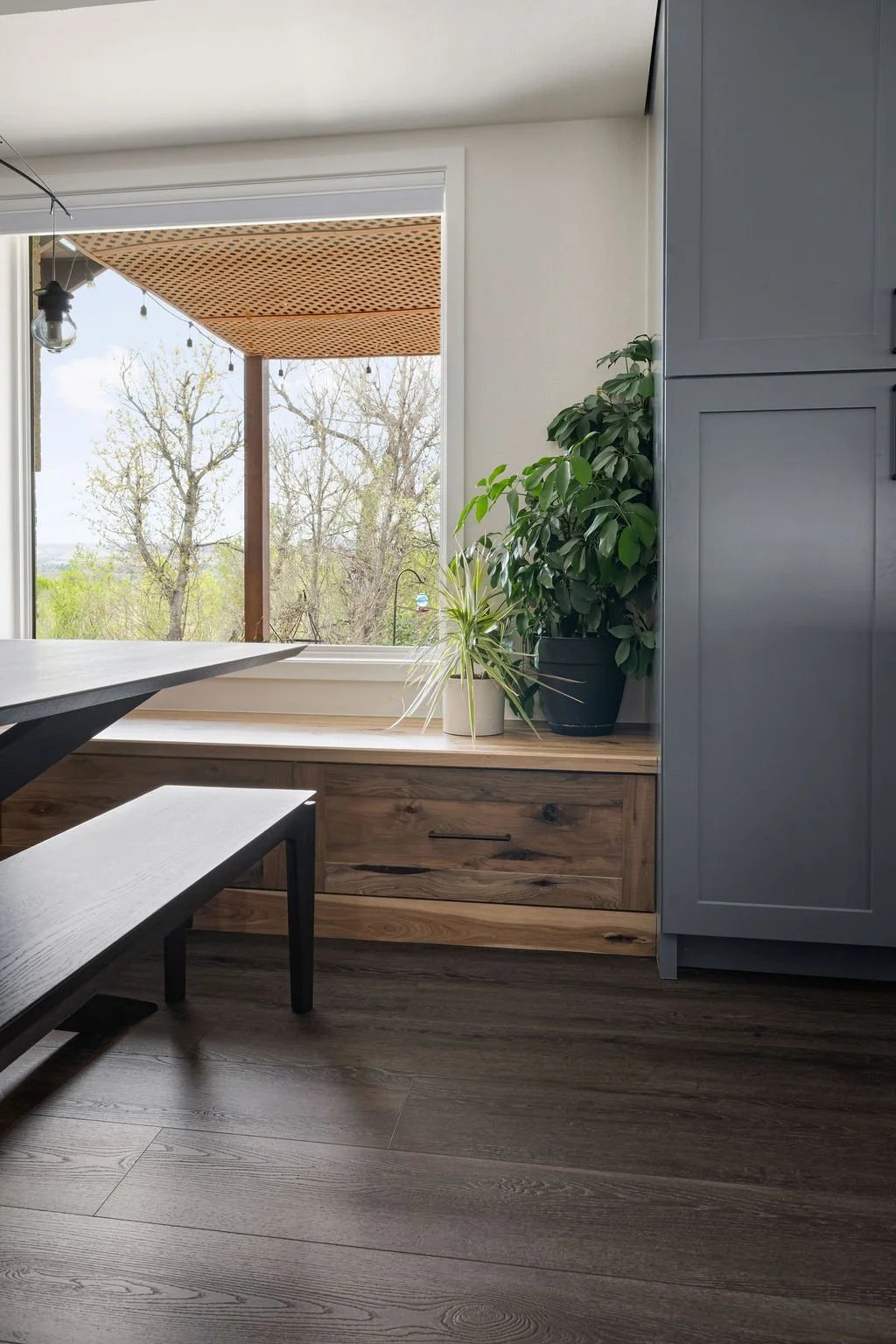 Custom built-in bench seating with natural wood finishes, expansive windows, and modern cabinetry designed to bring warmth and functionality into the kitchen space.