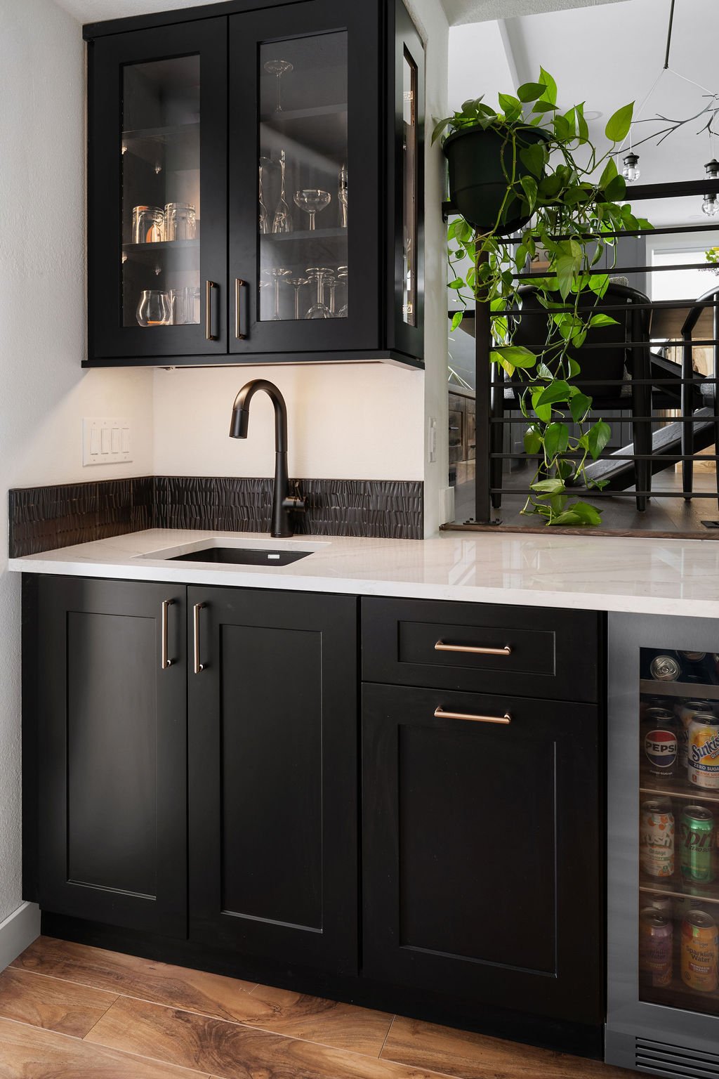 Custom bar area with black cabinetry, glass display cabinets, small sink