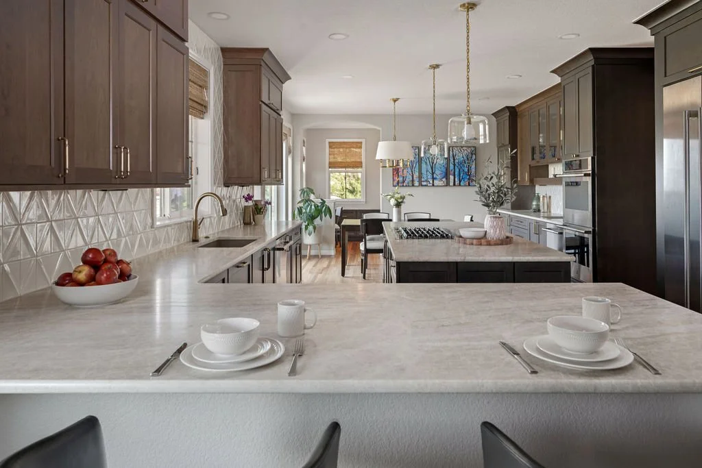 Open-concept kitchen with dark wood cabinetry, light stone countertops, a large island, and breakfast bar seating.