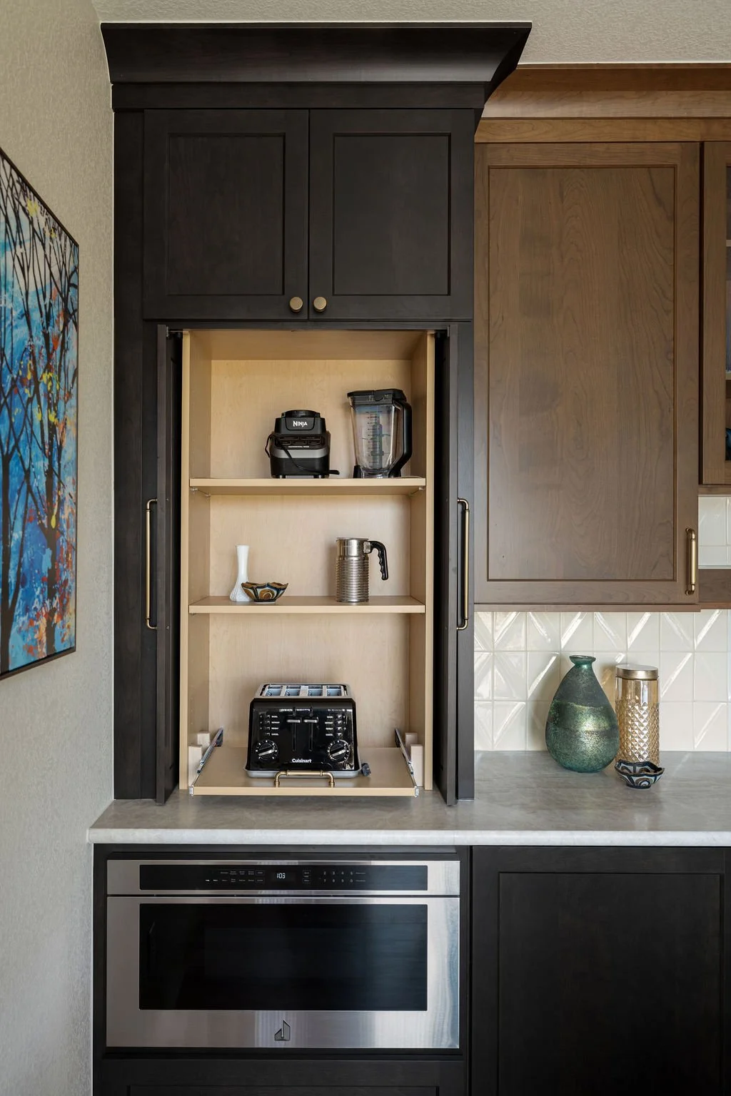 Built-in kitchen appliance cabinet with hidden storage, dark wood cabinetry, and light interior shelving.