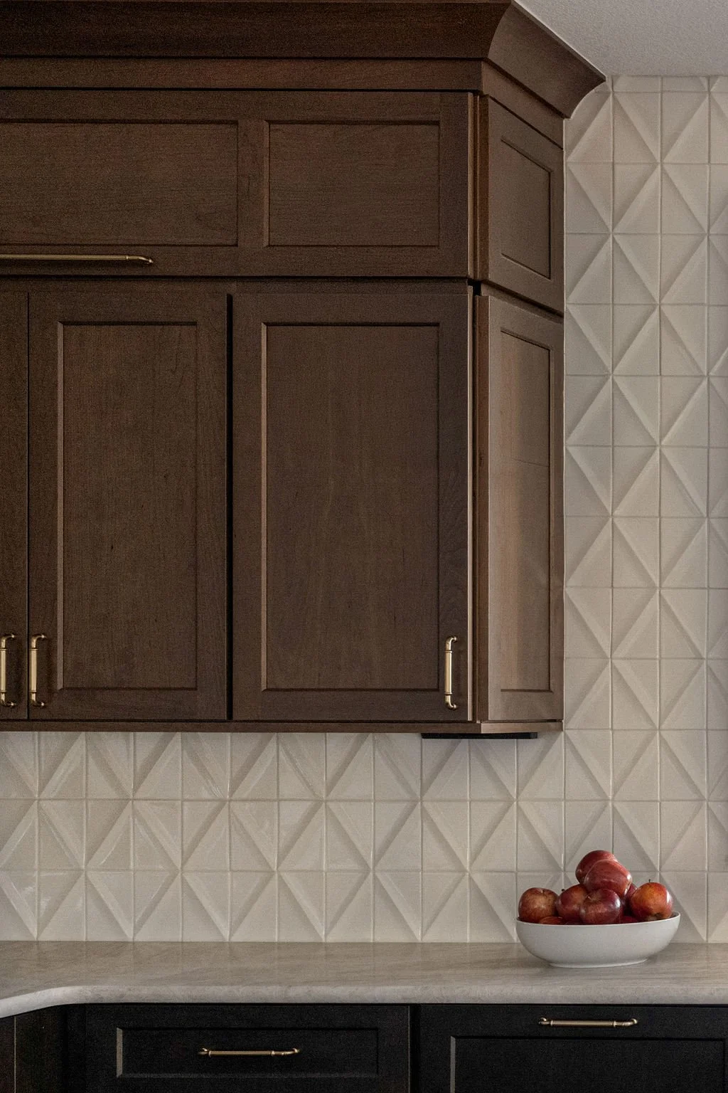 Dark wood kitchen cabinets paired with a textured geometric white tile backsplash.