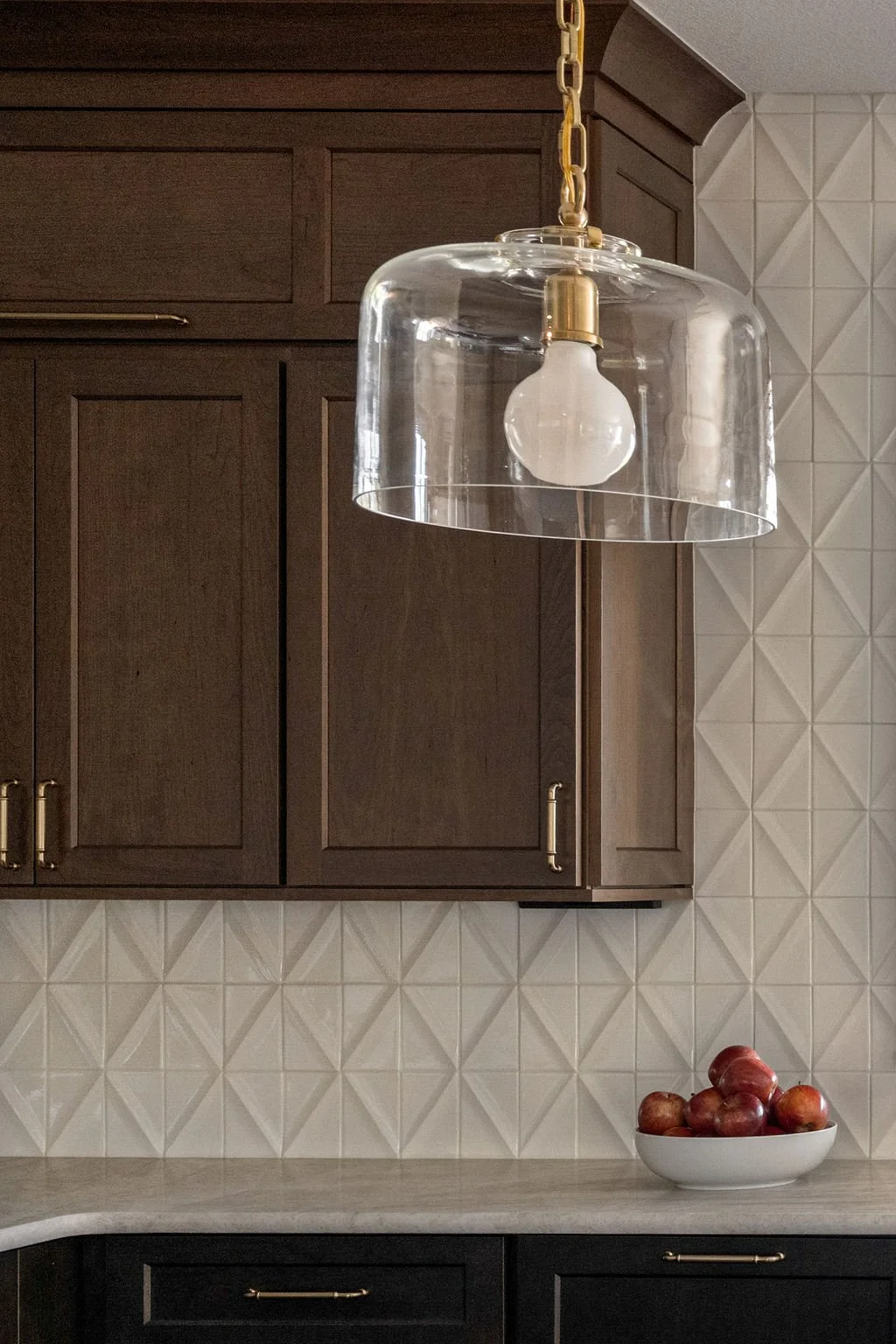 Custom kitchen cabinetry with geometric backsplash and glass pendant lighting