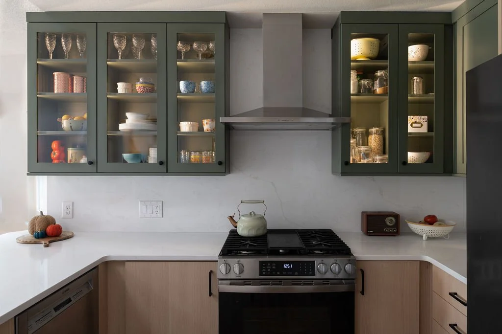 Green glass-front cabinets and stainless range in Highlands Ranch kitchen remodel