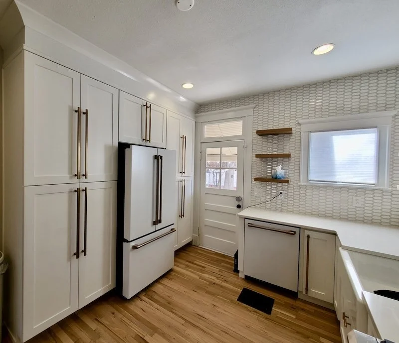 Custom white kitchen remodel in Highlands Ranch featuring shaker cabinets, farmhouse sink, open wooden shelving, and modern backsplash