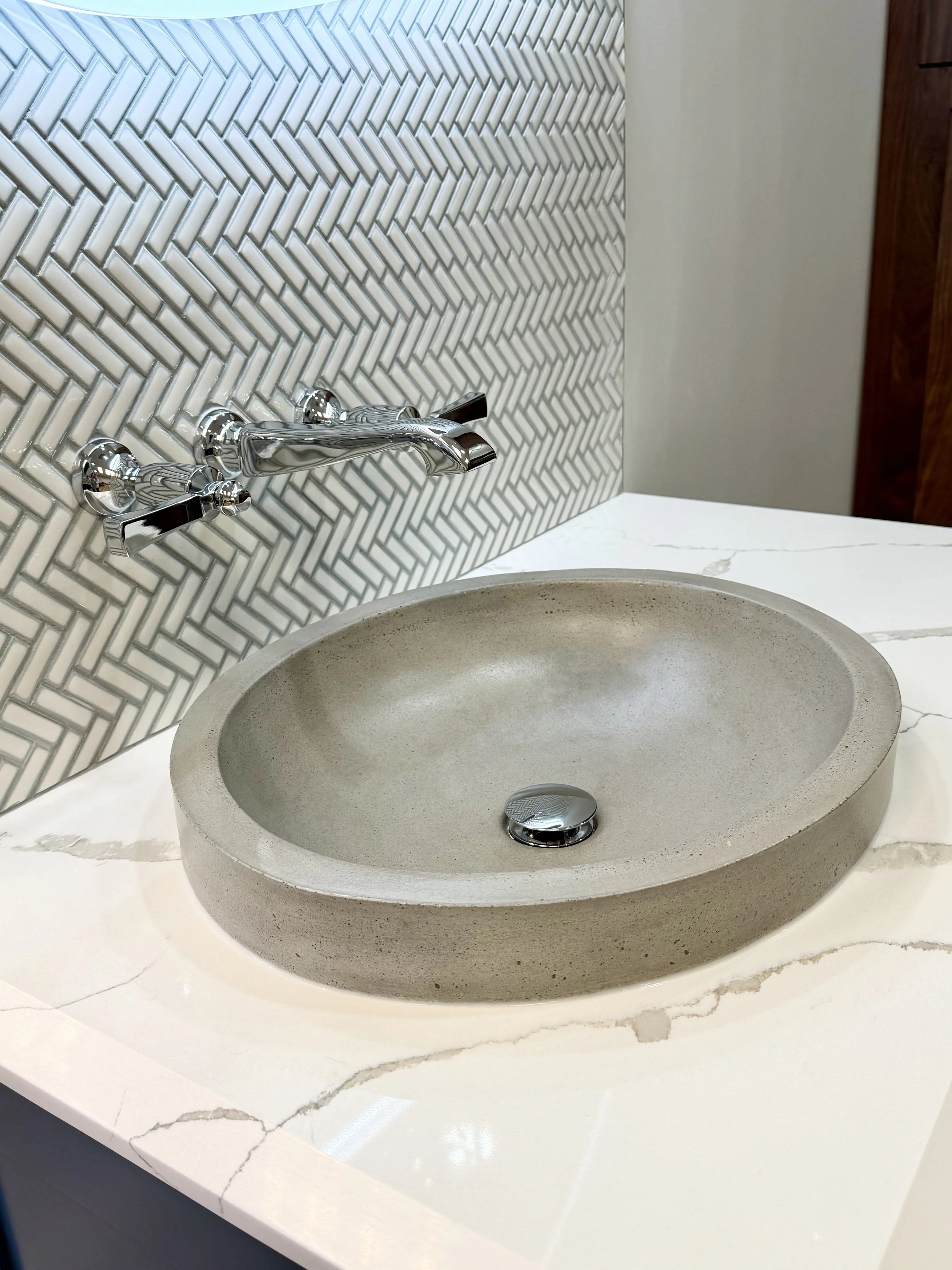 Elegant bathroom finishes featuring a handcrafted vessel sink, premium quartz surfaces, and sophisticated textured tile accents.
