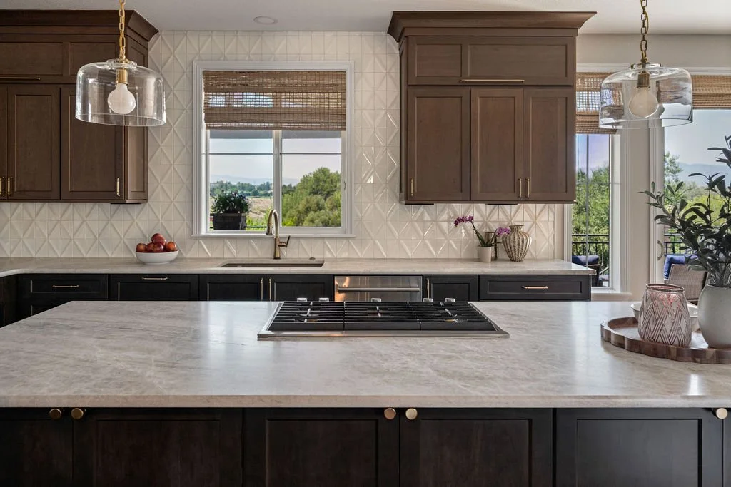 Modern kitchen with dark woodland cabinetry, a large stone island, pendant lighting.