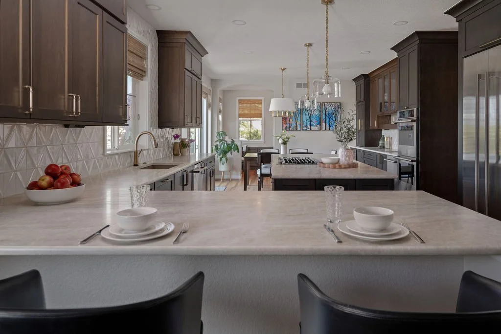 Open-concept kitchen with dark wood cabinetry, light stone countertops, a large island, and breakfast bar seating.