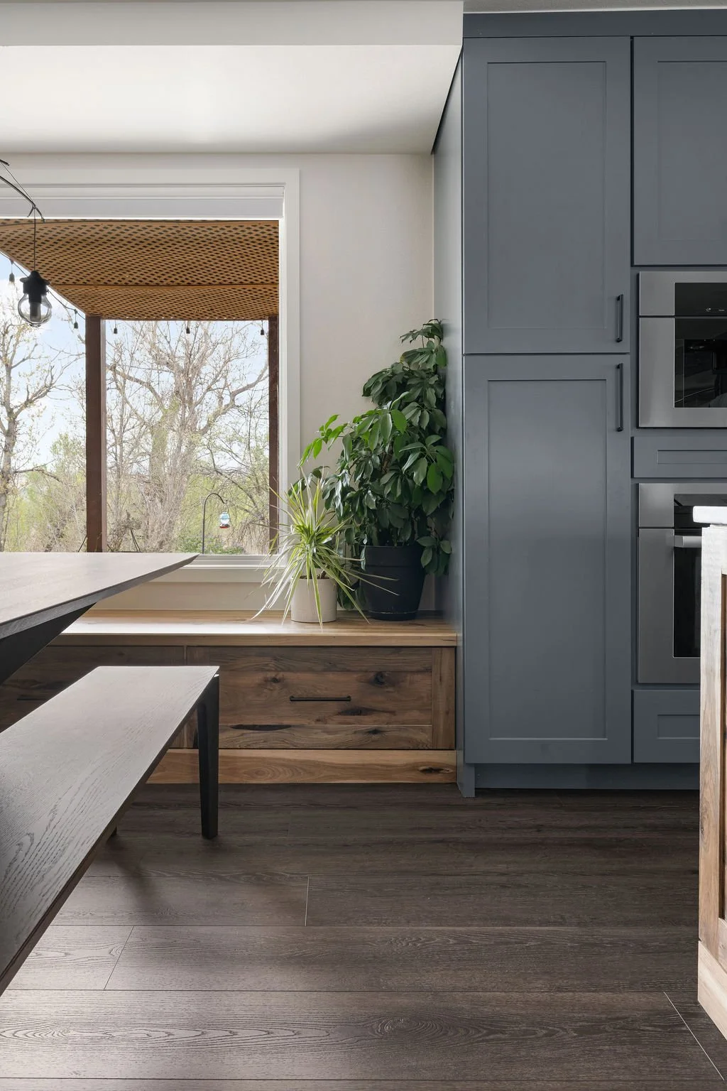 Custom kitchen window bench with wood drawers and tall gray cabinetry