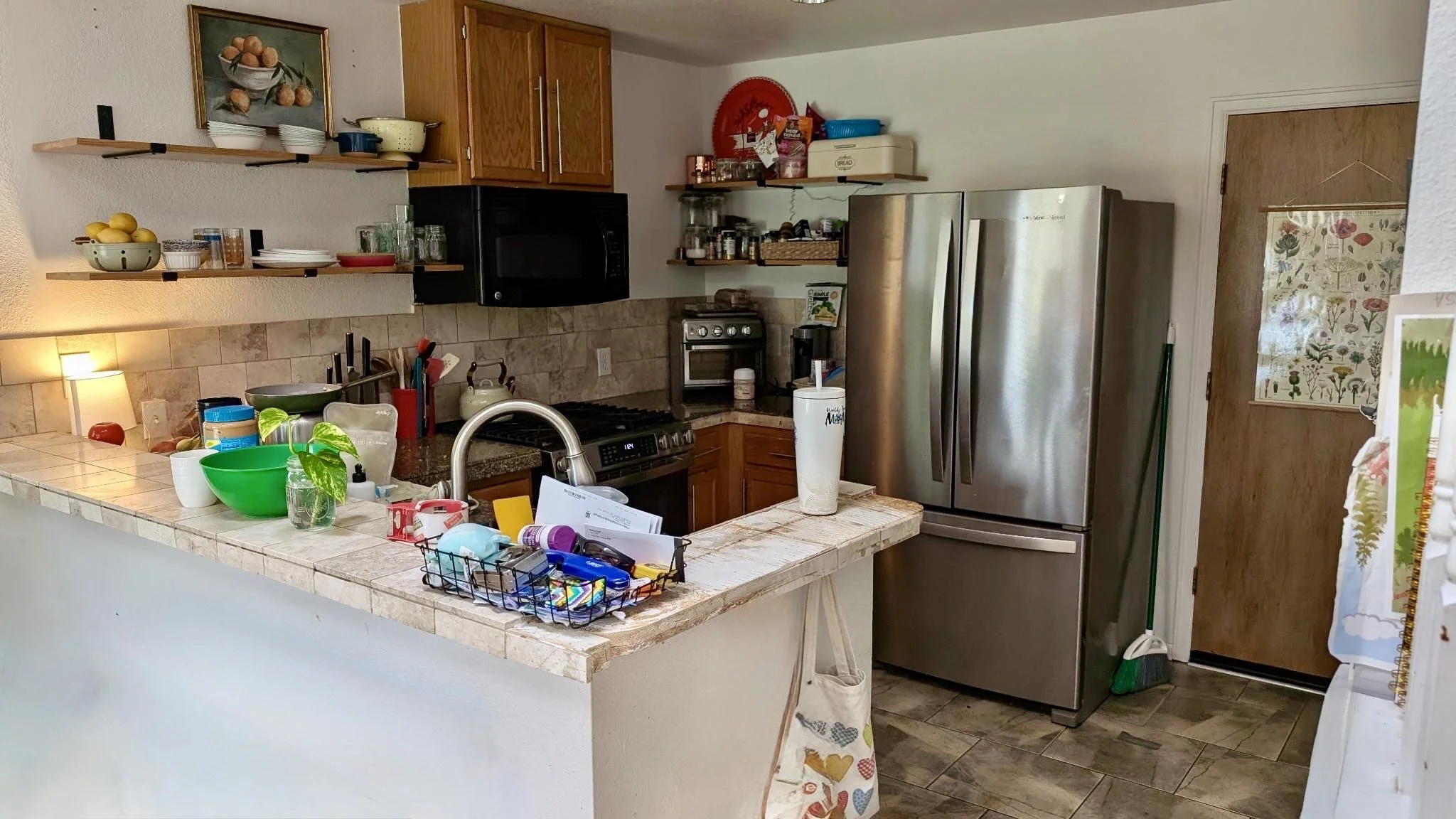 Before view of Highlands Ranch kitchen with wood cabinetry, open shelving, peninsula, and older finishes
