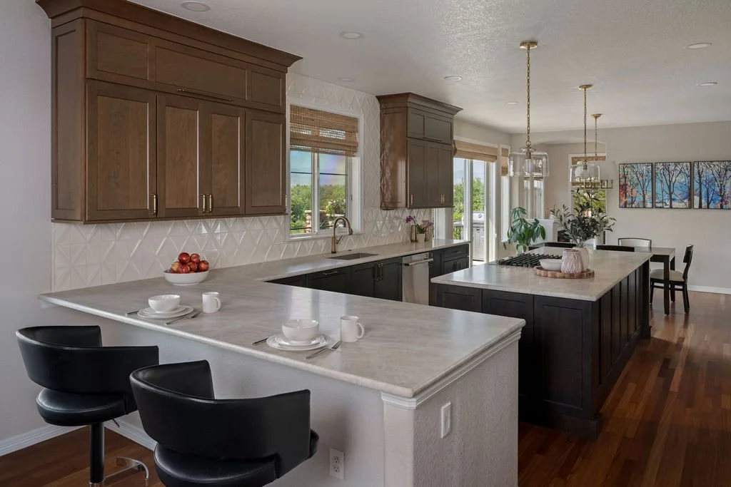 Spacious modern kitchen with dark wood cabinets, light countertops, breakfast bar seating, and pendant lighting.