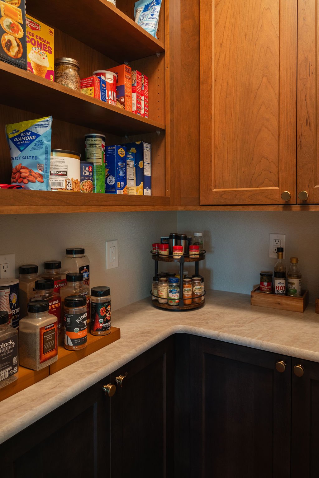 Walk-in pantry with wood cabinetry, countertop storage, and organized shelves for food and spices.