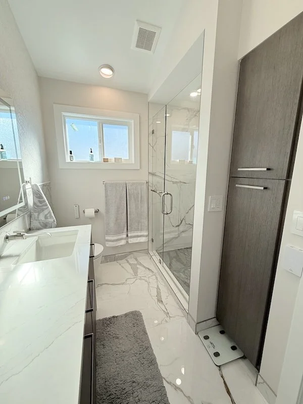 Contemporary bathroom remodel with sleek cabinetry, spacious glass shower enclosure, and elegant marble-inspired tile designed for a fresh modern feel.