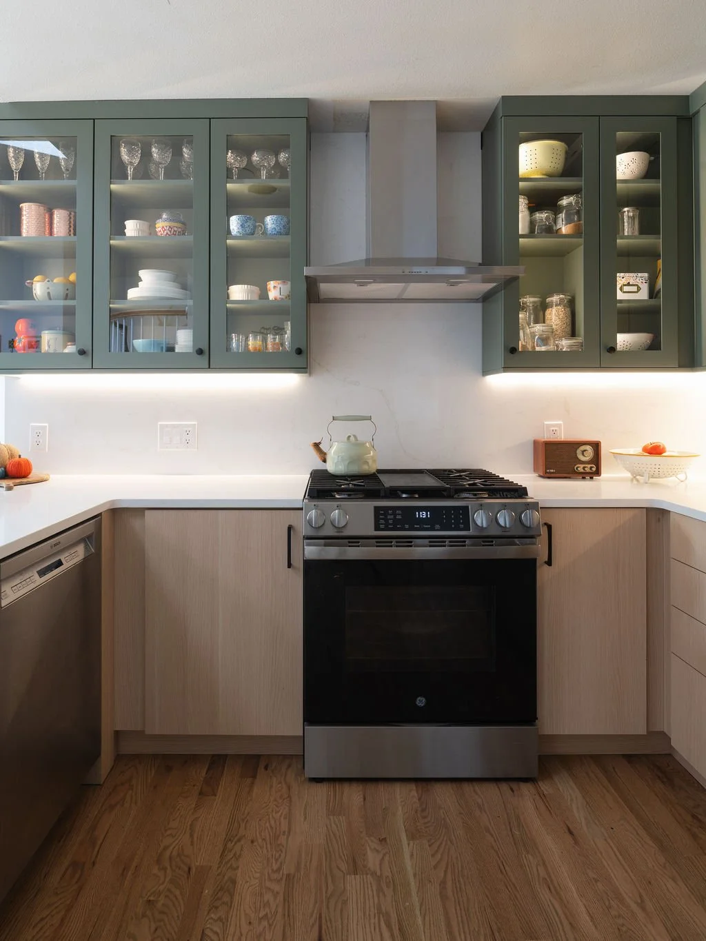 Green glass-front cabinets and natural wood cabinetry in Highlands Ranch kitchen remodel