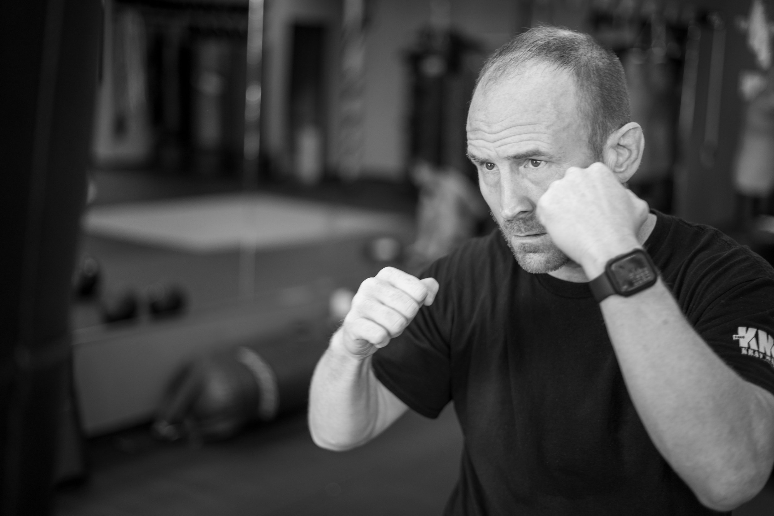 Black and white portrait of a Krav Maga instructor in a fighting stance at Tampa Bay Krav Maga. This intense training moment showcases the mental focus and readiness behind effective self-defense in Clearwater.