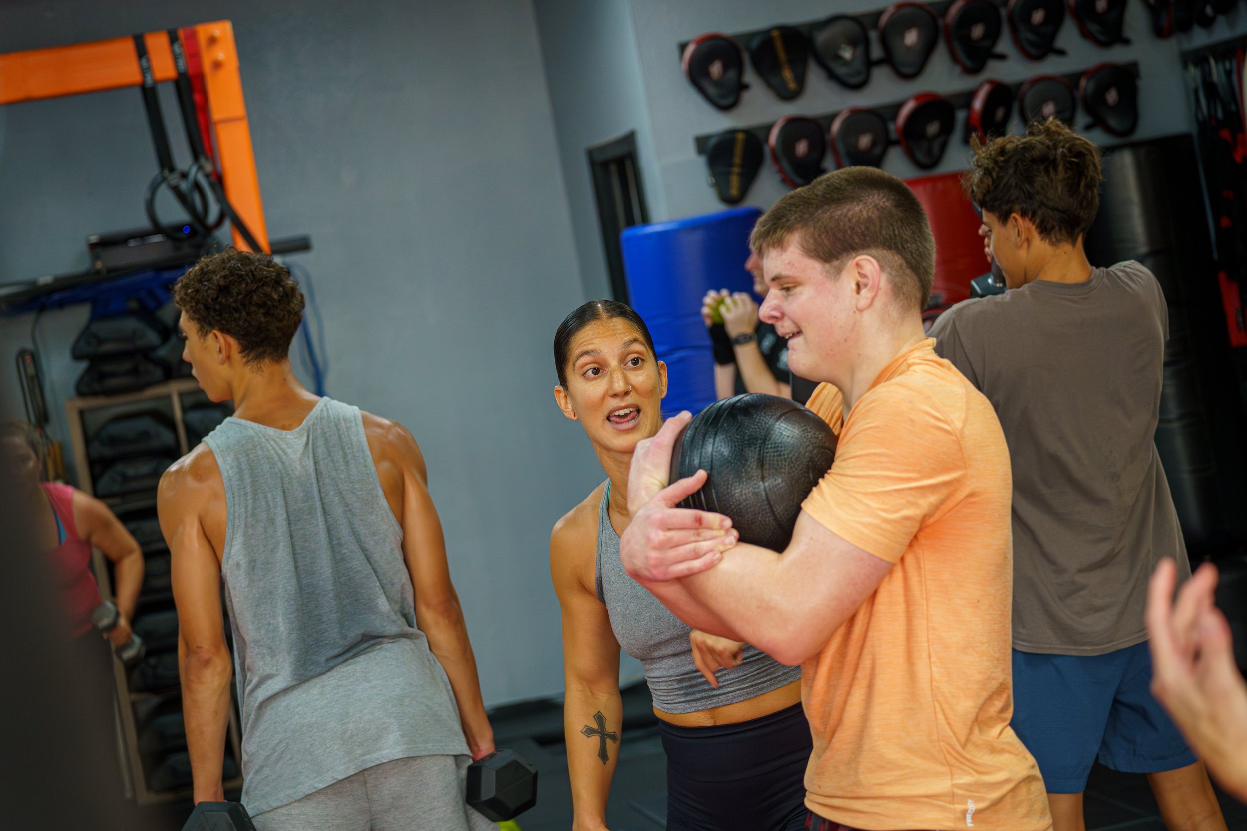 Fitness instructor supporting young client with medicine ball during Clearwater group session.