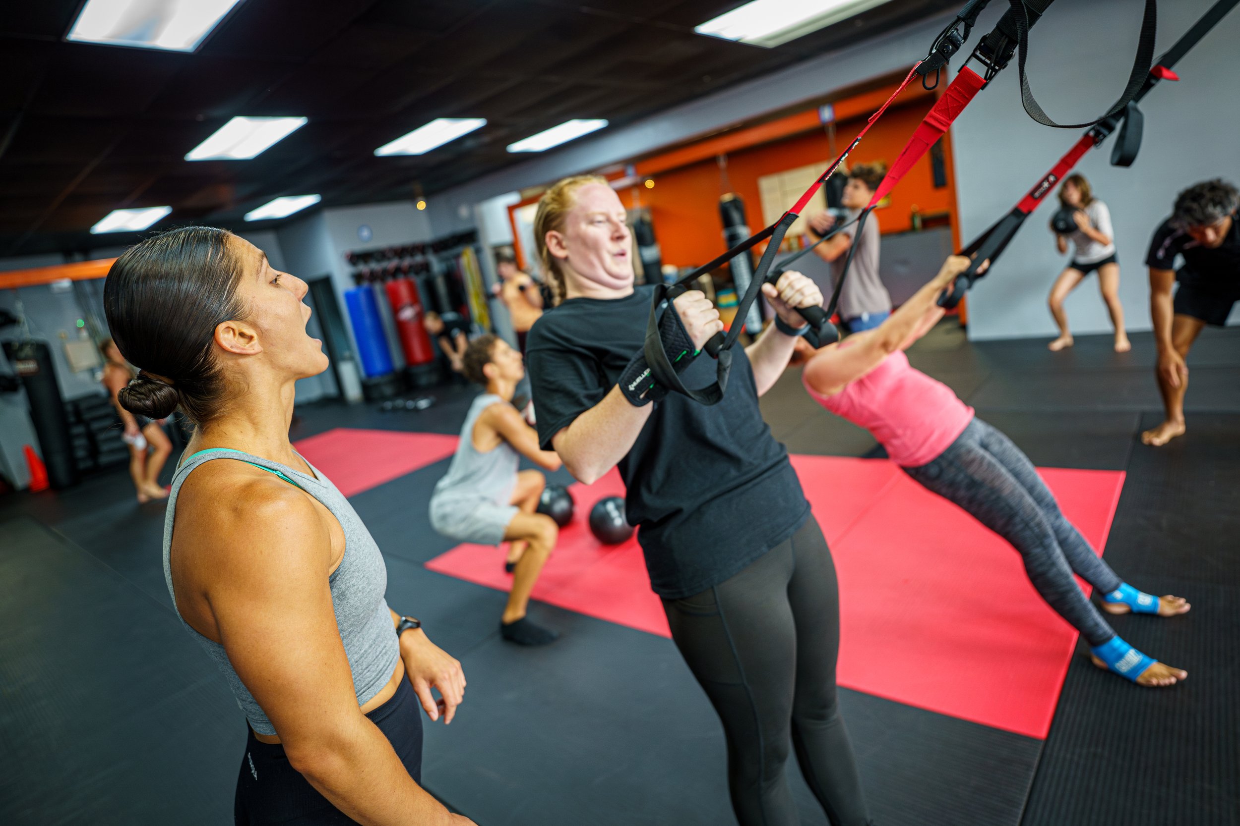 Group fitness training in Clearwater gym using TRX straps, guided by personal trainer.