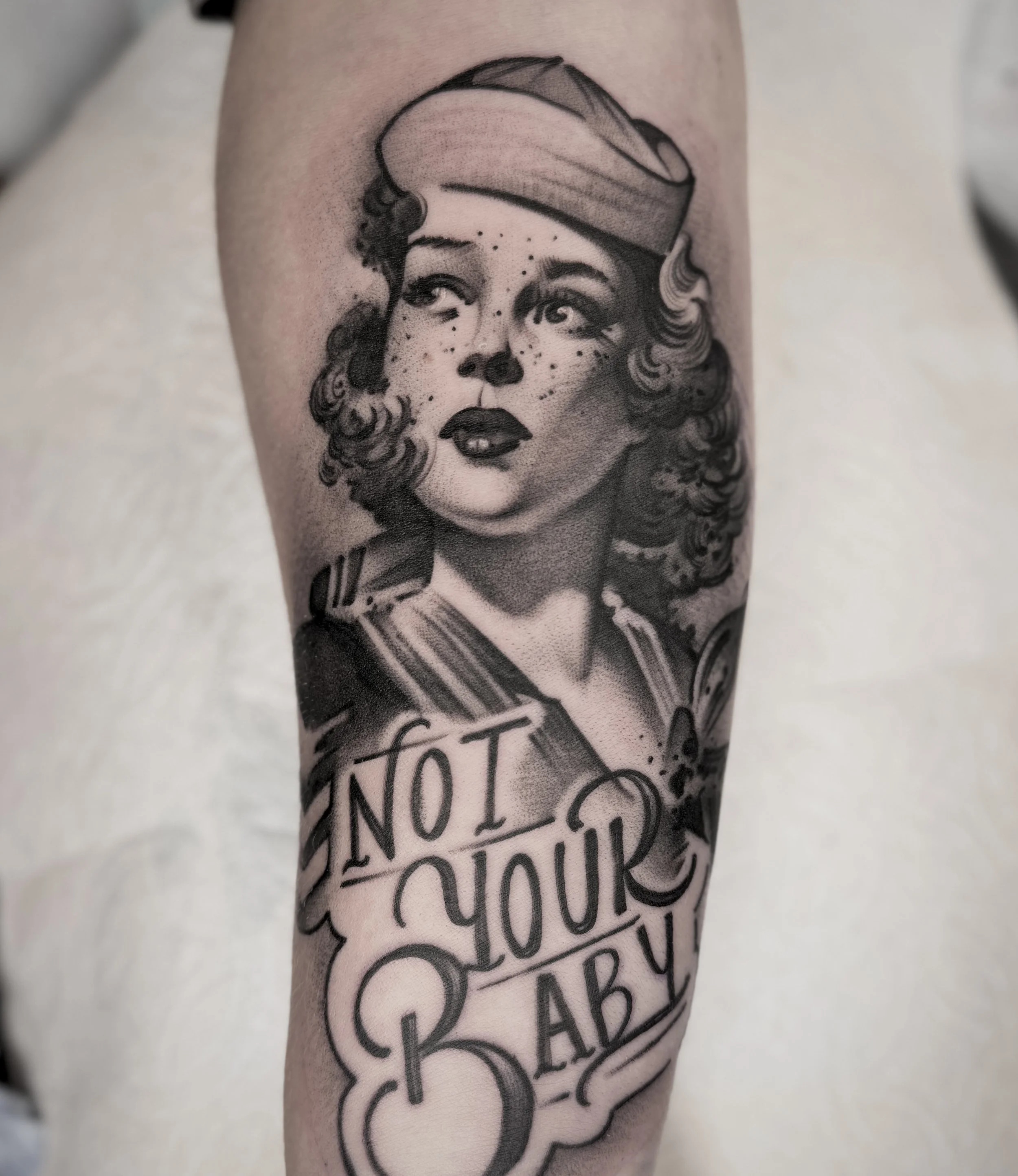 Stylized black and grey portrait of a sailor girl with bold “Not Your Baby” script below. Fierce and illustrative.